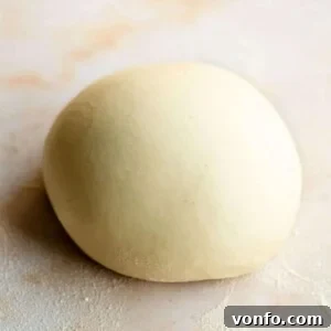 Hearty Eggless Semolina Pasta 7 A close up of semolina pasta dough in a ball on a marble surface