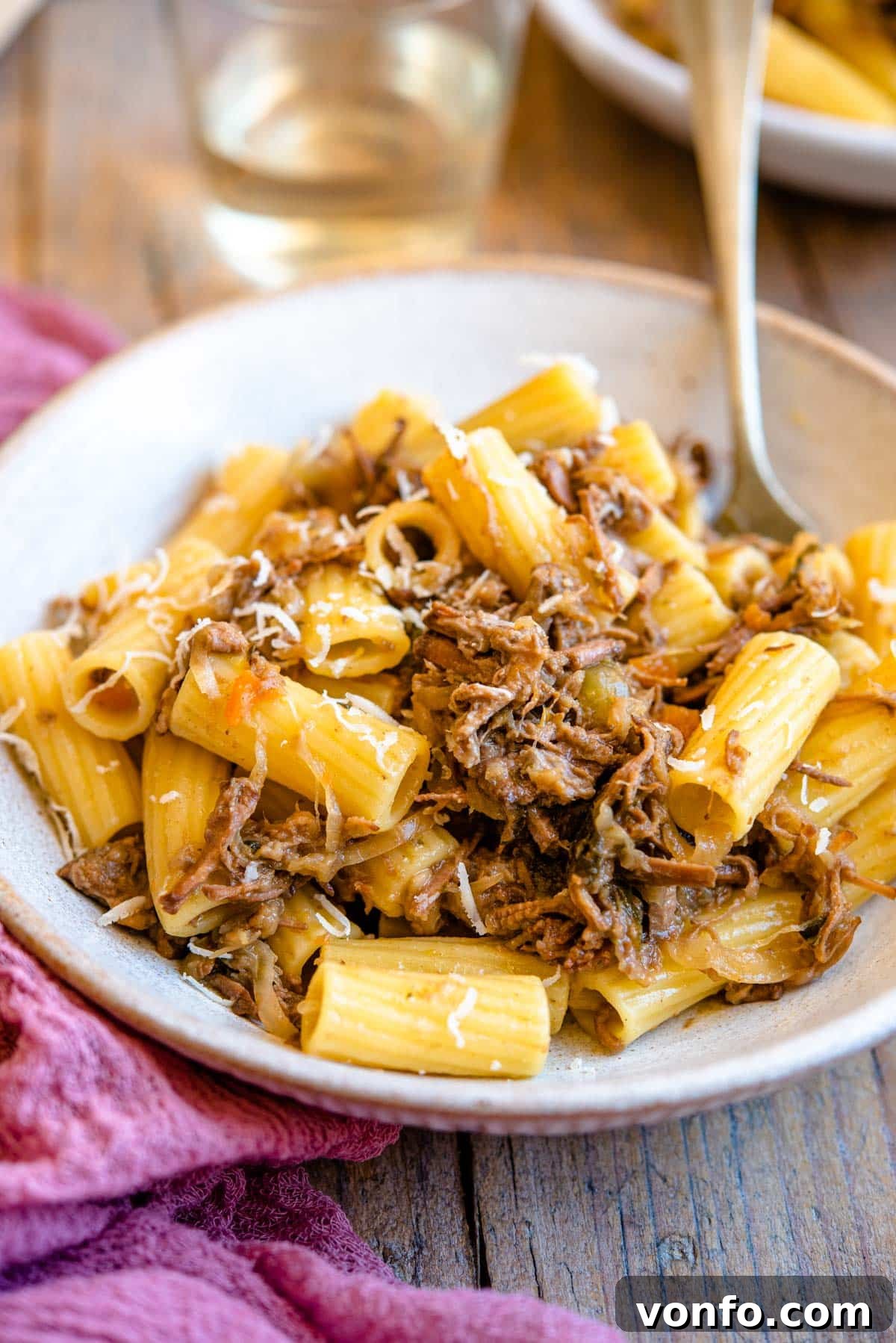 Neapolitan Genovese Sauce: Italy's Slow-Cooked Onion Masterpiece 3 A side shot of a Neapolitan ragu tossed with rigatoni pasta in a rustic bowl, showcasing the rich, glossy texture of the sauce and tender beef pieces. Fresh parsley garnish adds a touch of vibrancy.