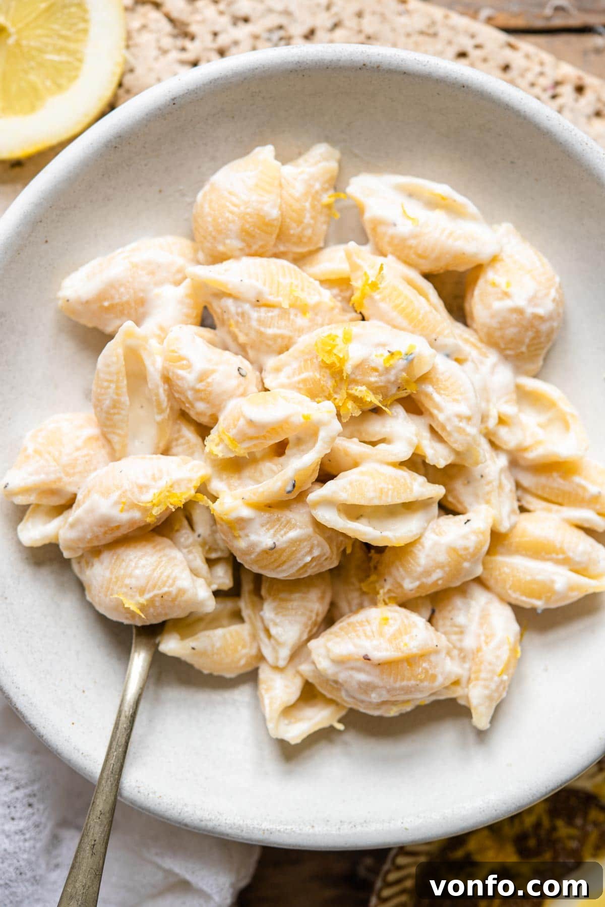 Two Irresistible Ricotta Pasta Sauces 3 An overhead shot of ricotta lemon pasta in a bowl with fresh lemon zest and a spoon