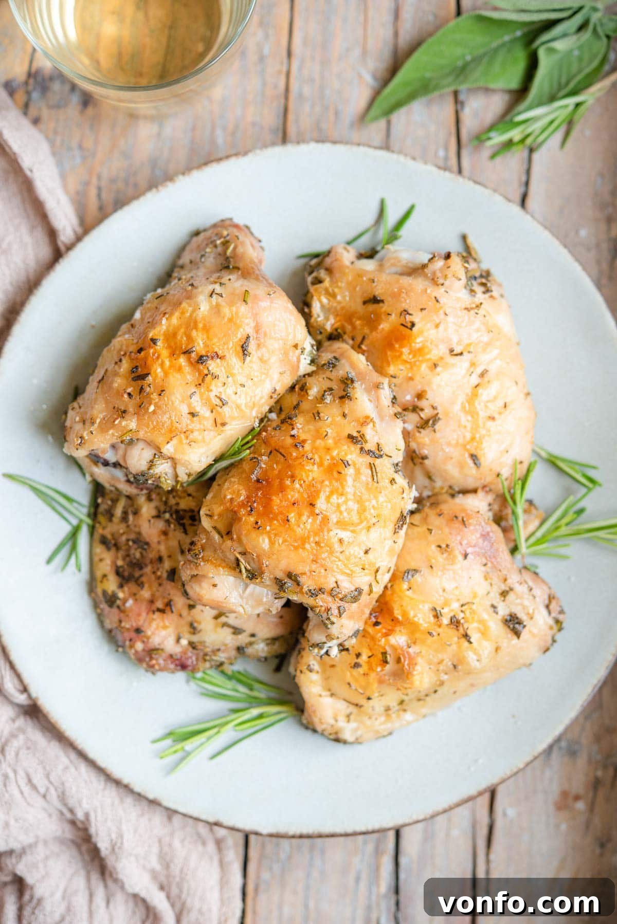 Garlic Parmesan Baked Chicken Thighs 2 An overhead shot of Italian baked chicken thighs on a plate with rosemary garnish, highlighting crispy skin.