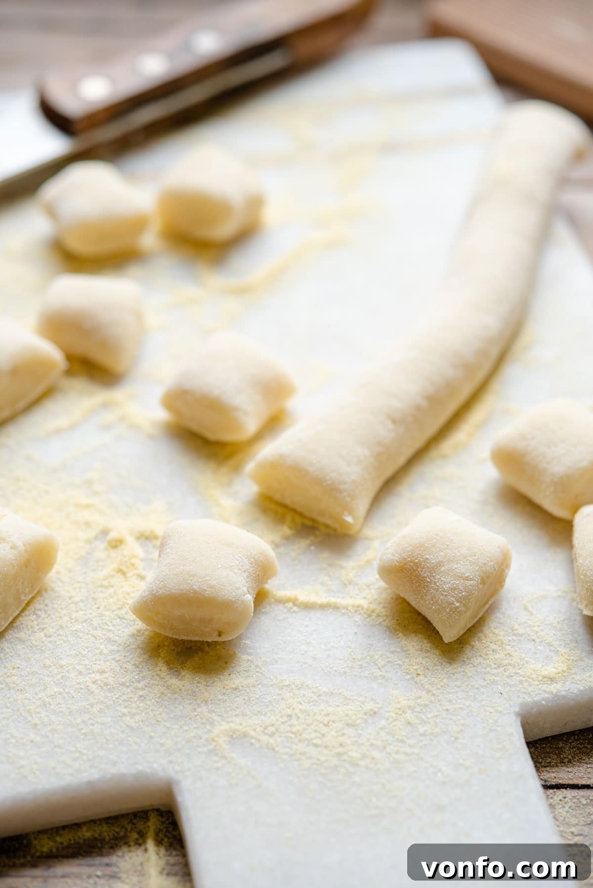 Crafting Perfect Homemade Potato Gnocchi 8 A close-up shot of perfectly textured gnocchi resting on a wooden cutting board, highlighting their soft and fluffy appearance.