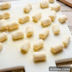 A side shot of potato gnocchi on a white marble cutting board