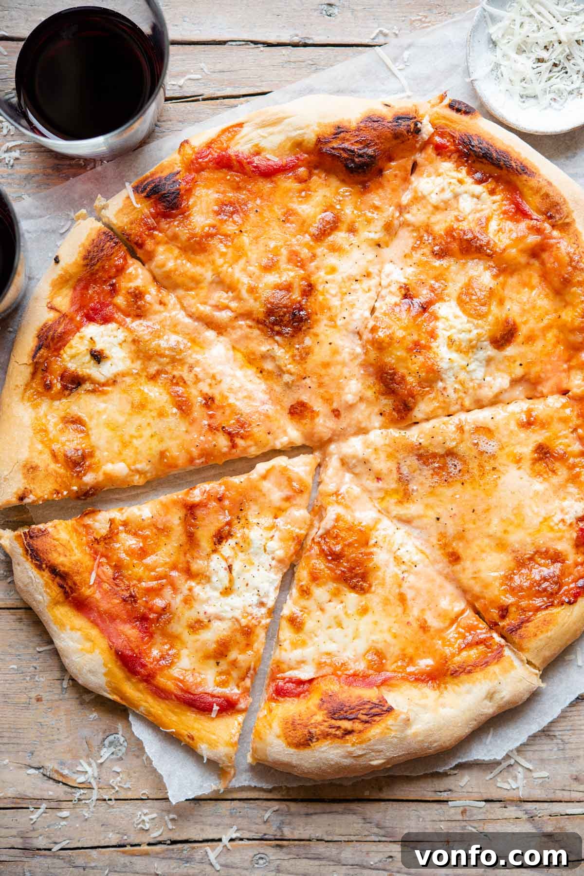 Ultimate Four Cheese Pizza 2 An overhead shot of a golden-brown, bubbly Quattro Formaggi pizza cut into perfect slices, showcasing its gooey melted cheese topping.