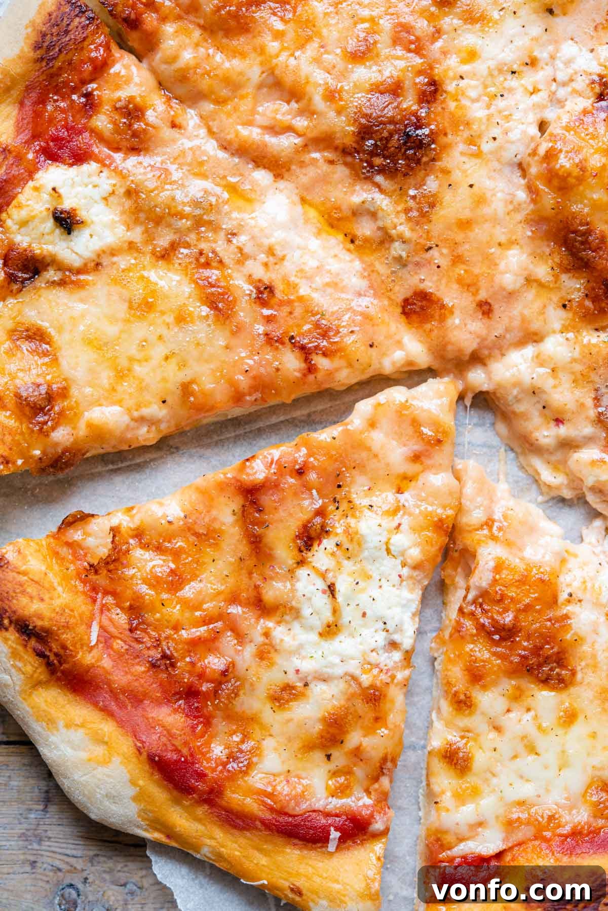 Ultimate Four Cheese Pizza 7 A close-up view of a perfectly baked slice of Quattro Formaggi pizza, showcasing the melted and bubbling cheese blend with a crispy crust.