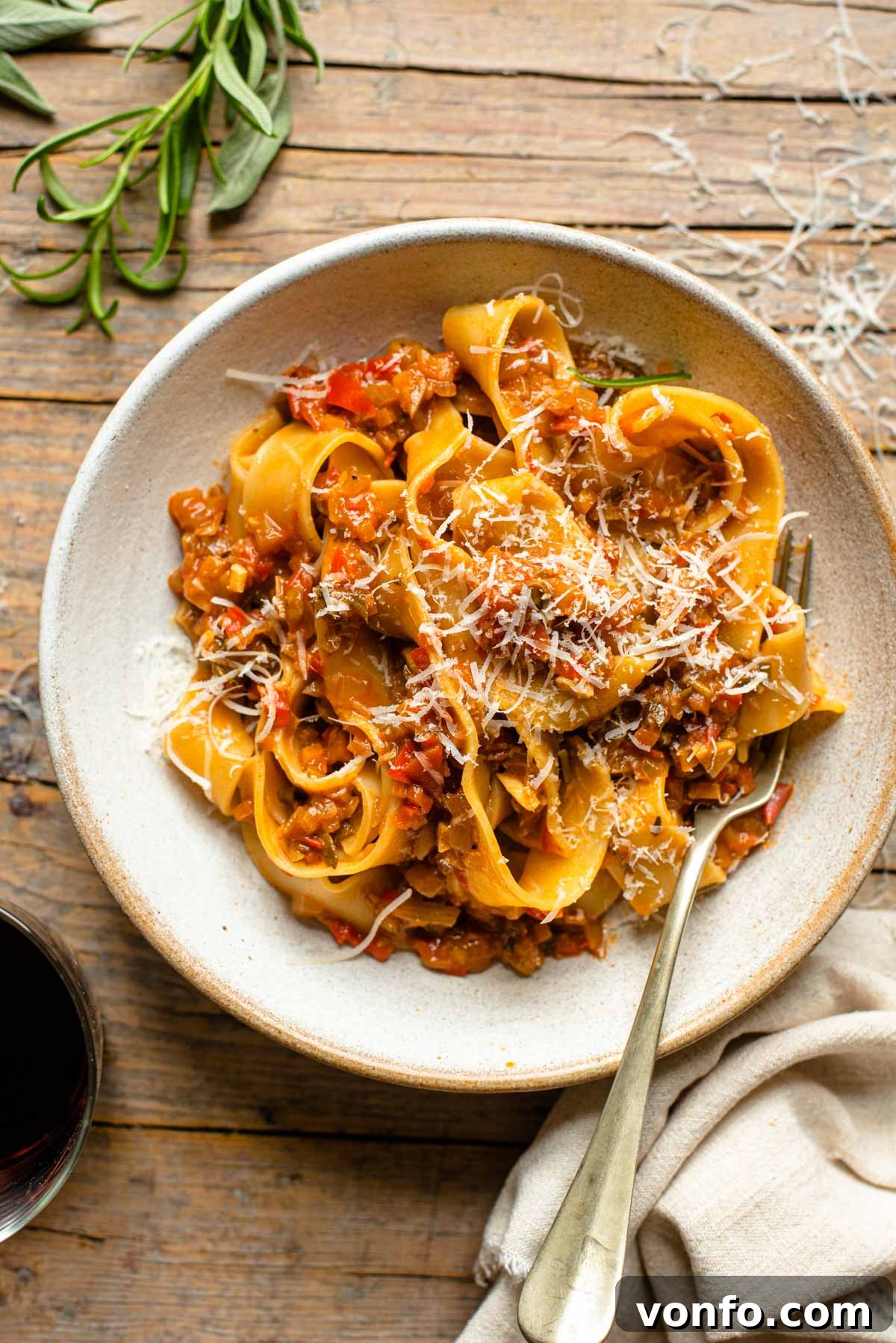 An overhead shot of a bowl of pasta with a vegetable sauce topped with parmesan cheese, ready to be served