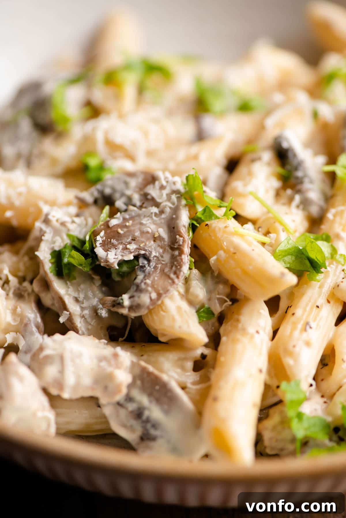 A large serving of freshly made Pasta alla Boscaiola in a rustic bowl, garnished with fresh parsley and grated Parmesan cheese, ready to eat.