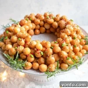 Struffoli honey balls arranged in a festive ring shape on a cake stand, generously covered in colorful sprinkles.