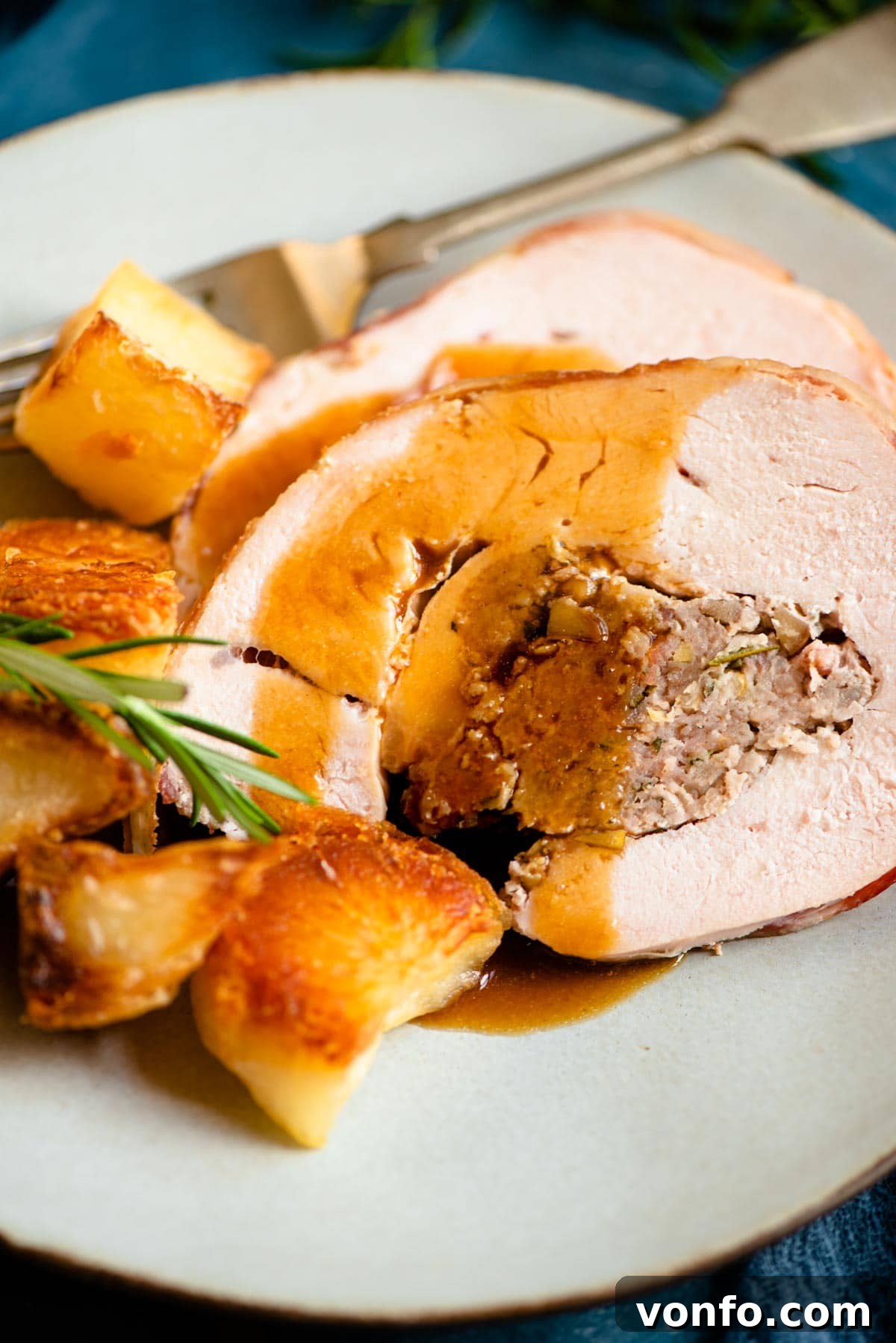 Savory Sausage and Chestnut Stuffed Turkey Breast 9 A close up of slices of stuffed turkey breast on a plate with gravy