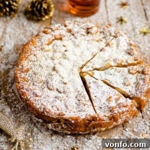A close up of panforte on a wooden board dusted with powdered sugar