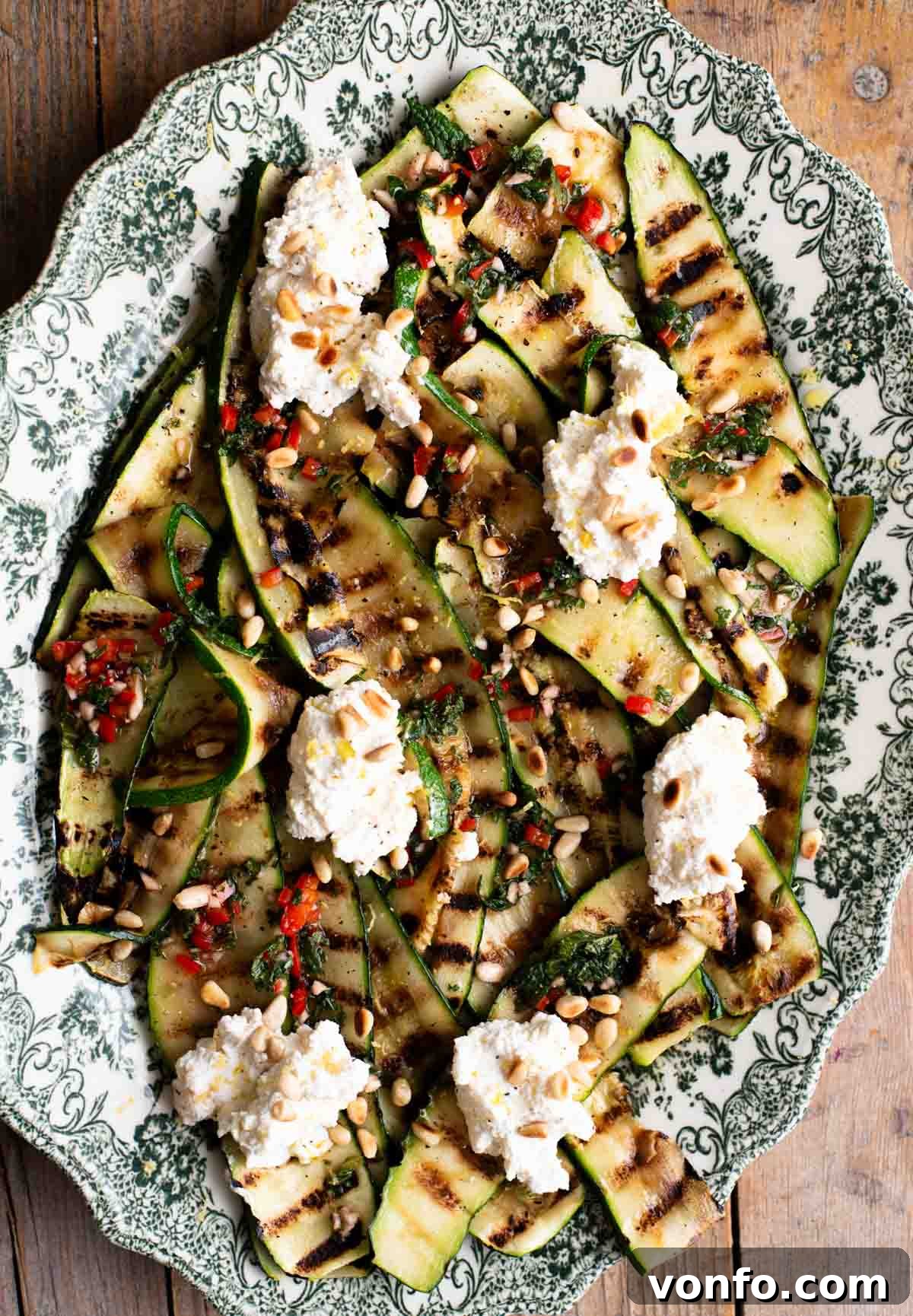 Grilled Zucchini with Creamy Ricotta and Toasted Pine Nuts 2 An overhead shot of grilled zucchini on a serving platter topped with garlic, chilli, mint and ricotta.