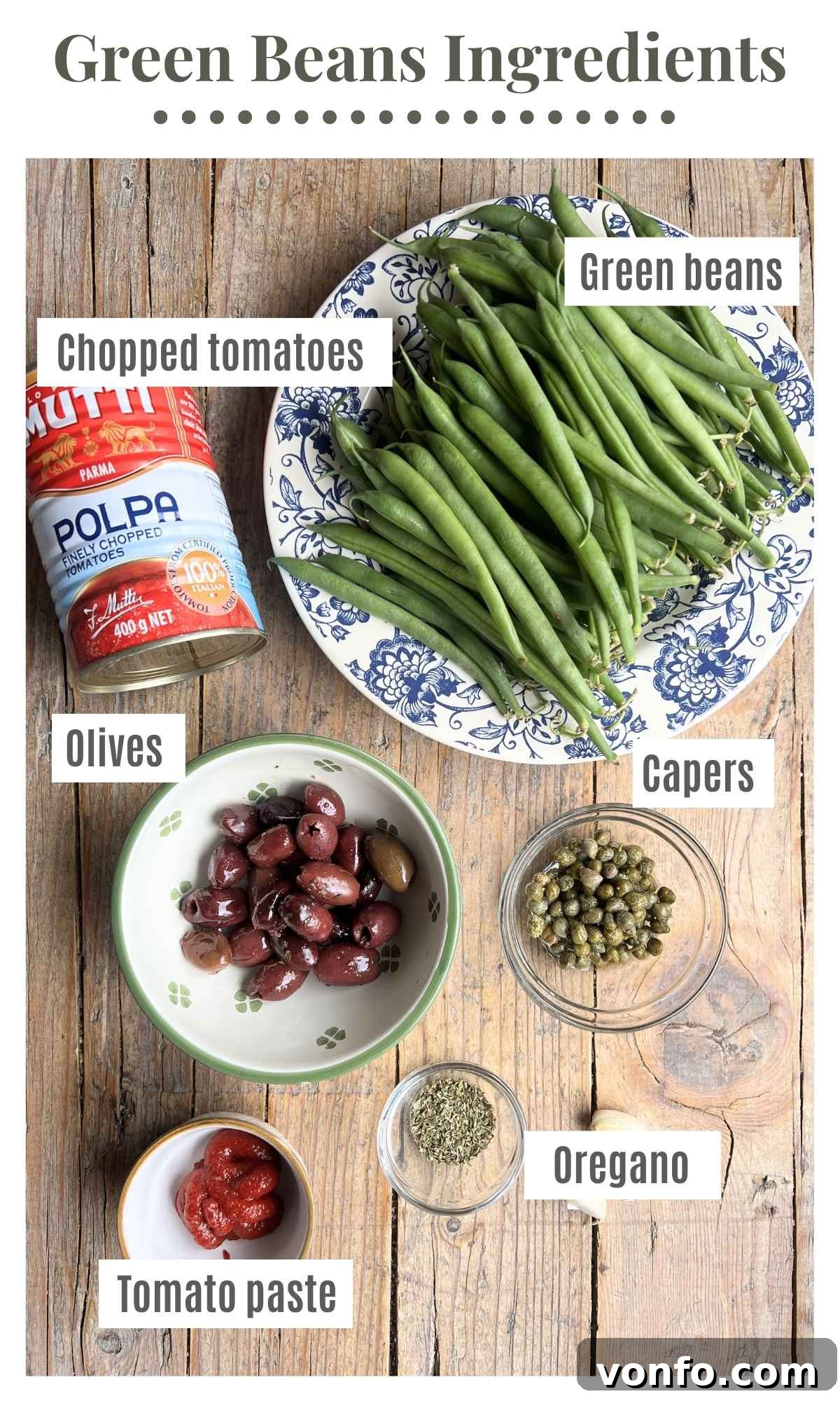 Zesty Green Beans with Olives and Capers 3 High-quality canned tomatoes, fresh green beans, assorted olives, briny capers, dried oregano, and rich tomato paste laid out on a rustic wooden board, perfectly prepared for cooking.