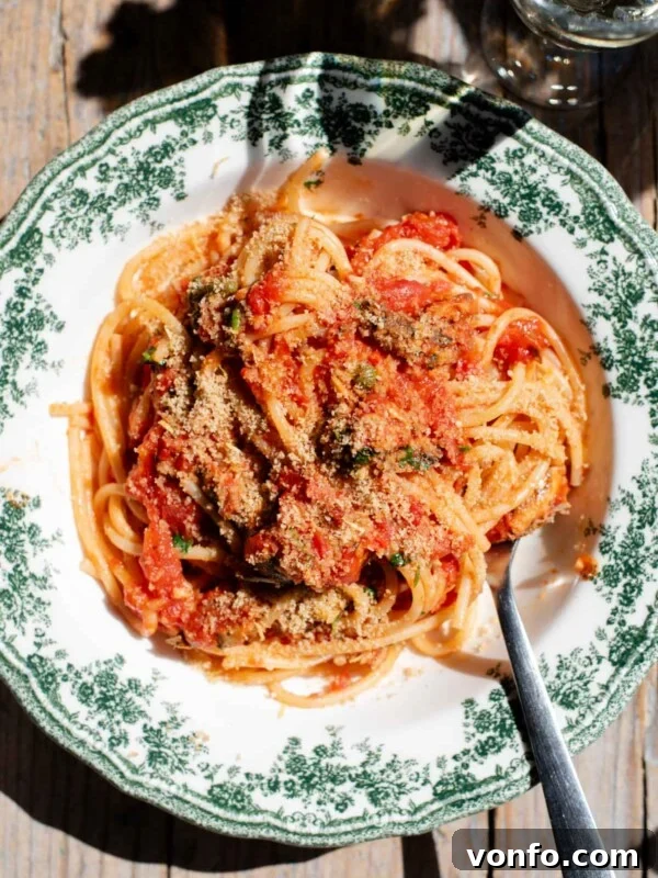 Sicilian Pistachio Pasta with Shrimp and Lemon Cream 5 An overhead shot of spaghetti in a tomato sauce with sardines and breadcrumbs on top. The bowl is a vintage style green and white colour.