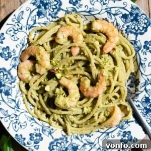 Sicilian Pistachio Pasta with Shrimp and Lemon Cream 9 A close up of pistachio spaghetti with shrimps on a blue floral plate.