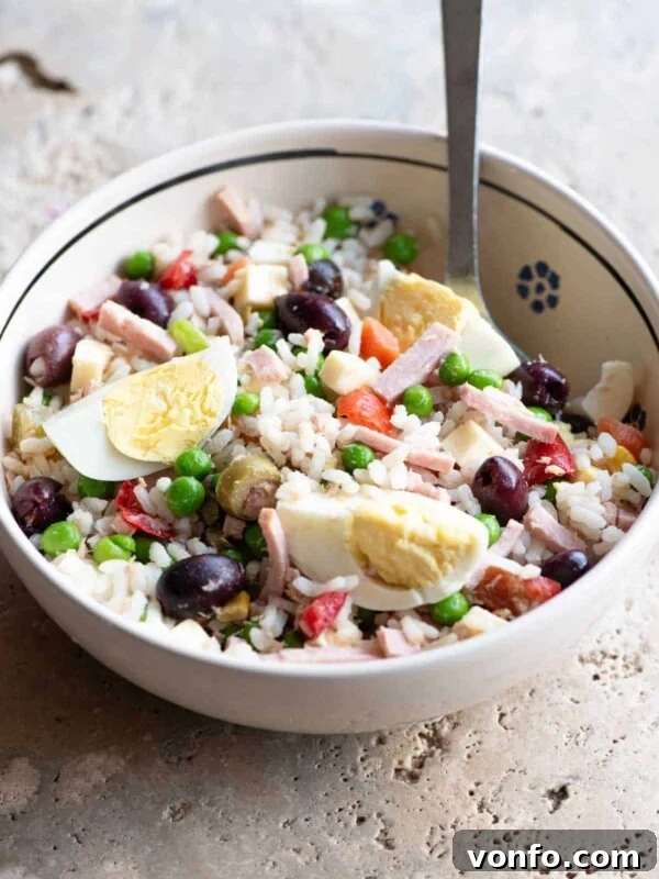 A traditional Italian rice salad in a bowl sitting on a rustic stone work top.