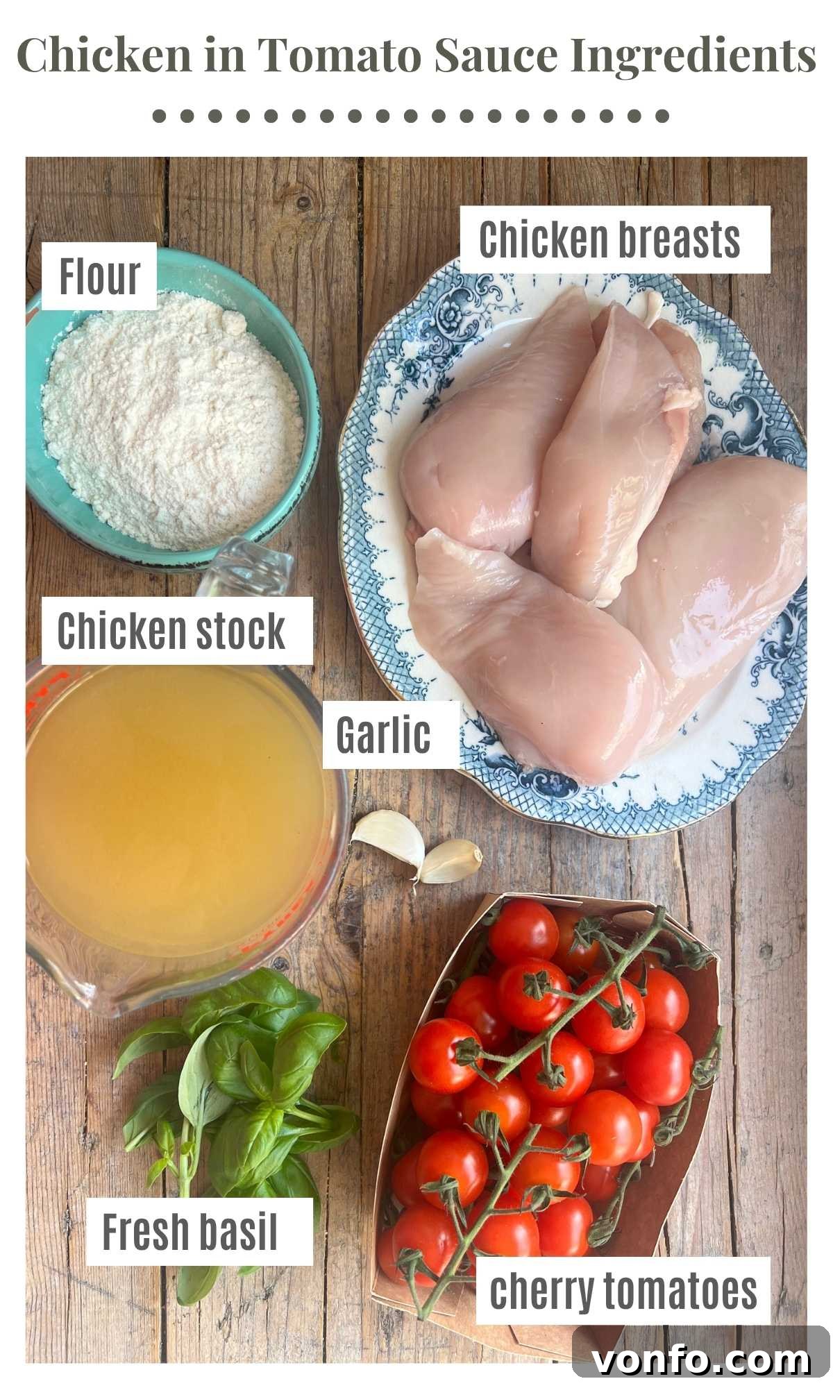 Cherry Tomato Basil Chicken Skillet with Garlic and Parmesan 3 An overhead shot showing ingredients laid out on a rustic wooden board. The ingredients are labelled; flour, chicken breasts, cherry tomatoes, chicken stock, fresh basil, garlic.