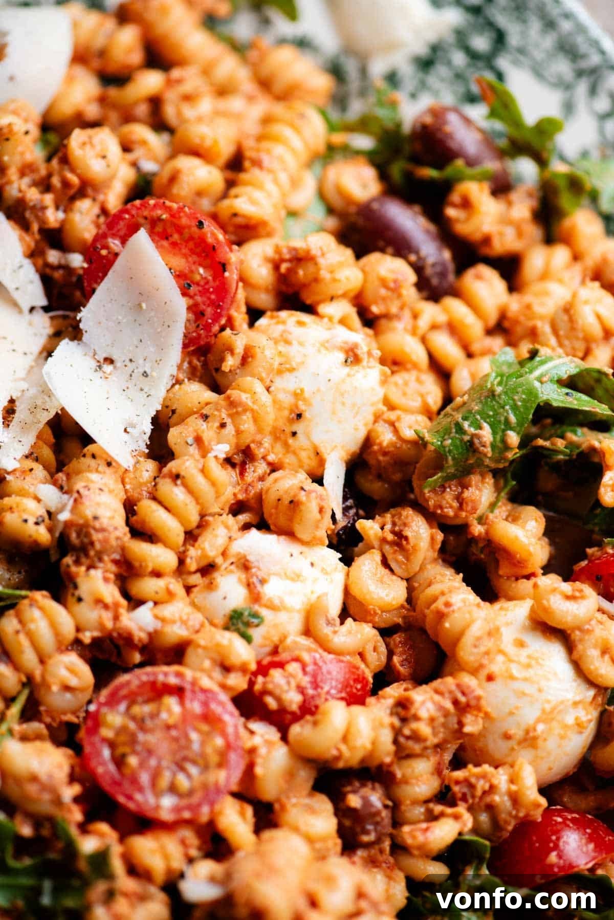 Sun-Dried Tomato Pasta Fredda: Chilled Mediterranean Pasta Salad 4 A close up of a pasta salad with a sun-dried tomato sauce, olives, mozzarella and fresh cherry tomatoes.