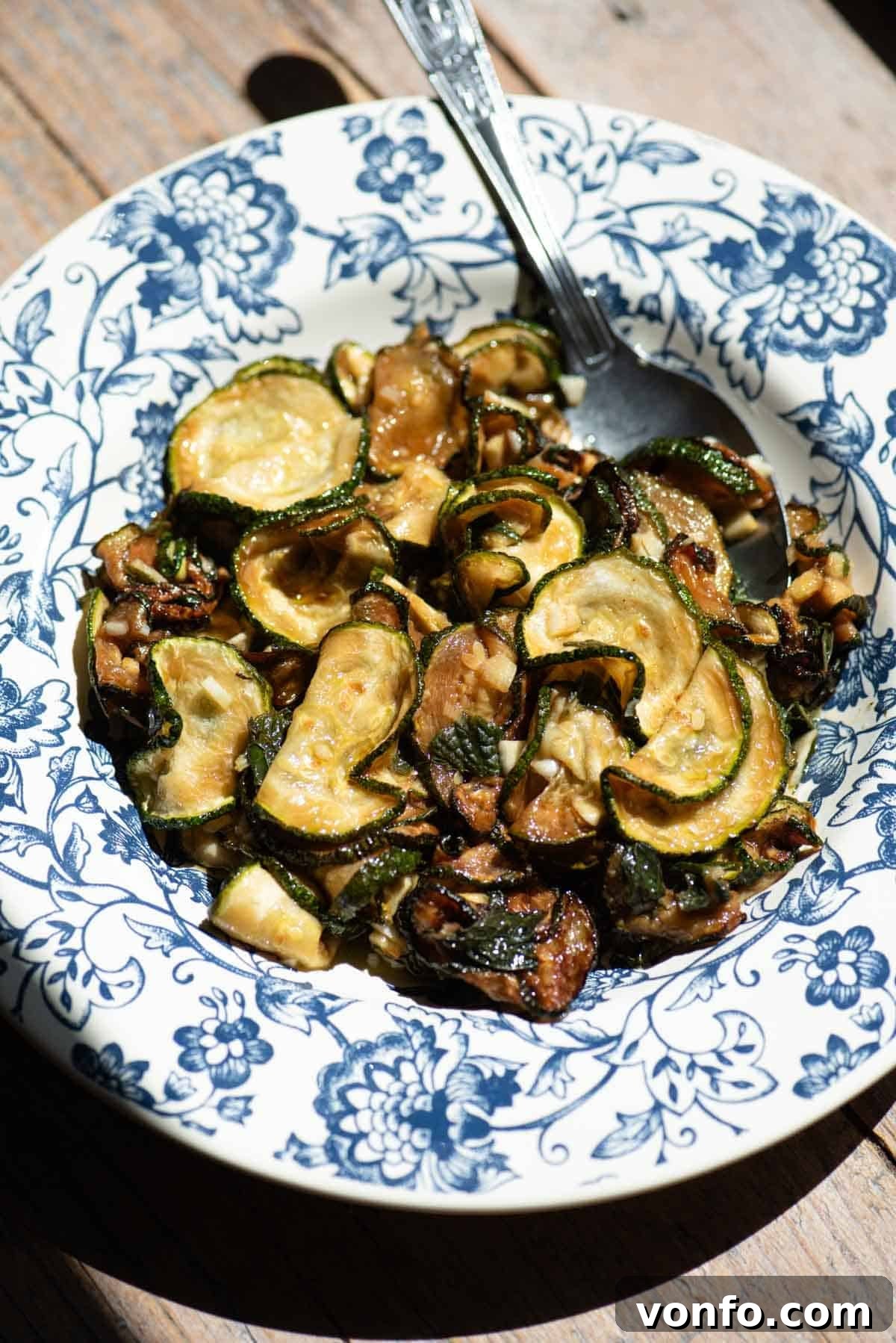 Neapolitan Zucchine alla Scapece: Fried Marinated Zucchini 2 A blue and white floral bowl filled with fried marinated zucchini and a spoon.