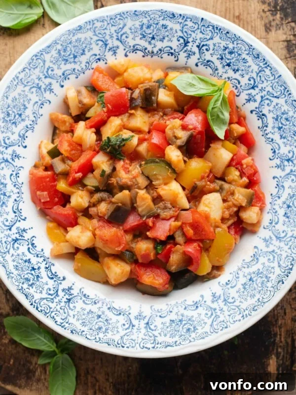 An overhead shot of Ciambotta (Italian vegetable stew) in a blue bowl, the background is wooden.
