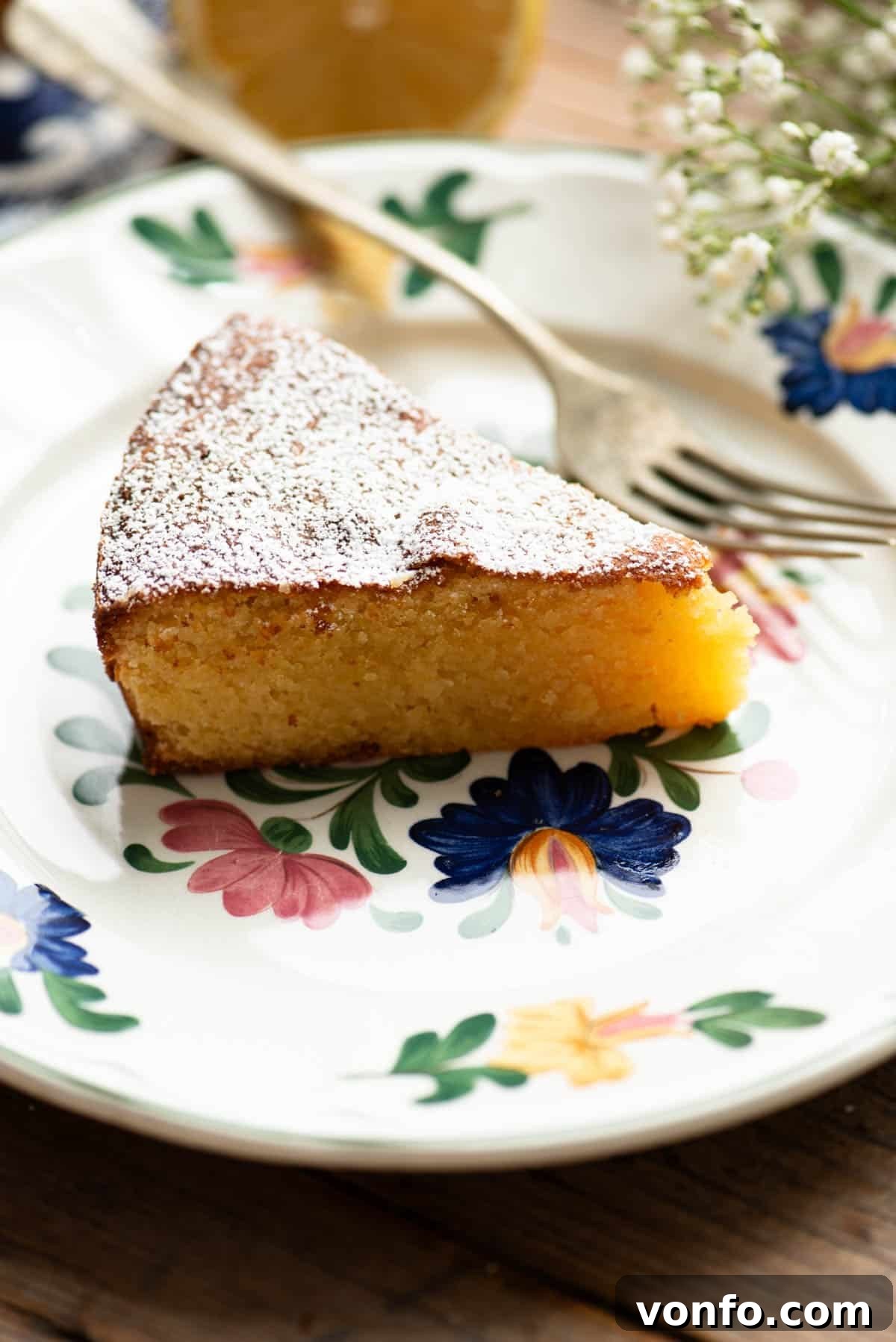 Torta Caprese Bianca: Italian Lemon White Chocolate Cake 4 A close up of a slice of white chocolate caprese cake on an Italian floral plate.