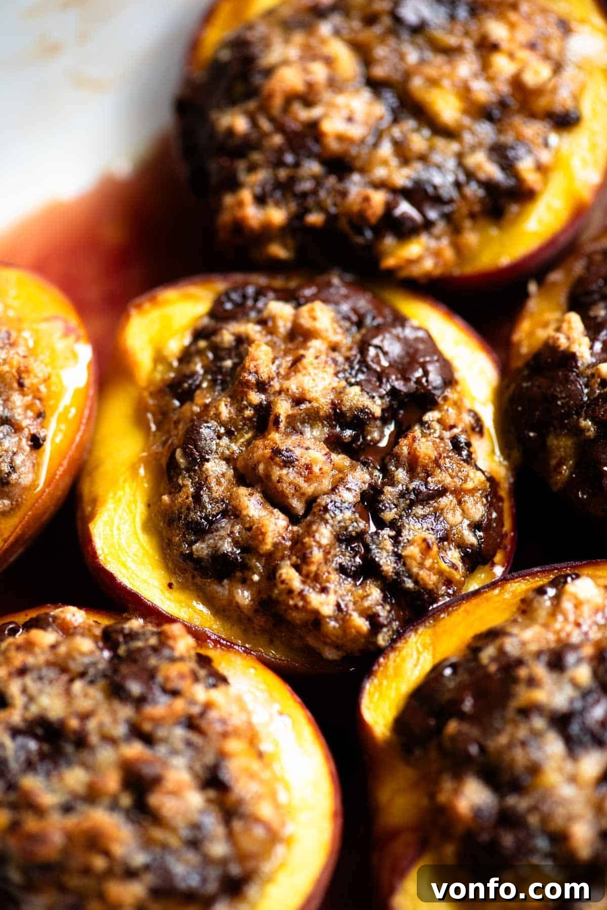 Piedmont-Style Baked Stuffed Peaches (Pesche Ripiene) 4 A close up of a baked peach stuffed with amaretti cookies and chocolate in a baking dish.
