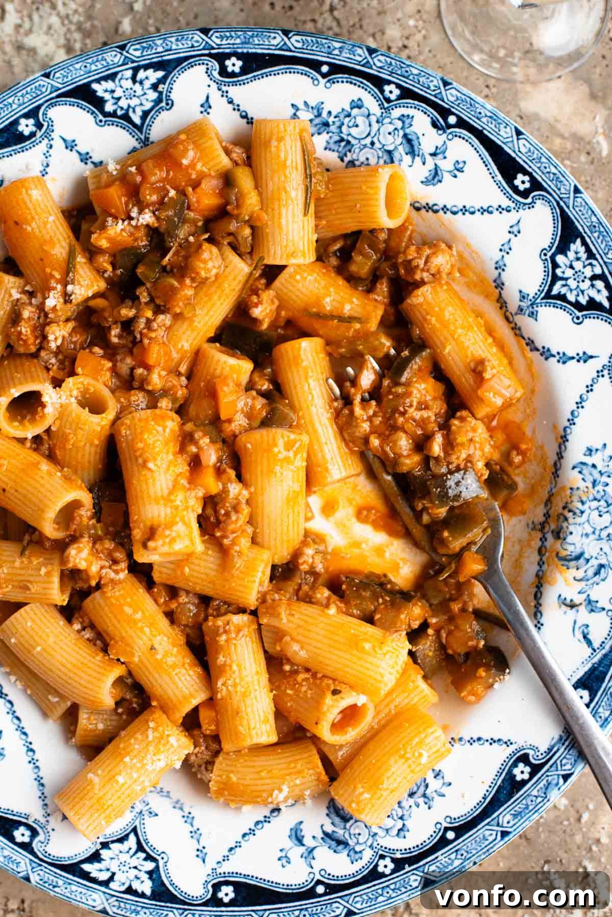 Slow-Braised Eggplant and Sausage Ragu 4 A close up of rigatoni pasta with a sausage and eggplant ragu in a blue and white bowl.
