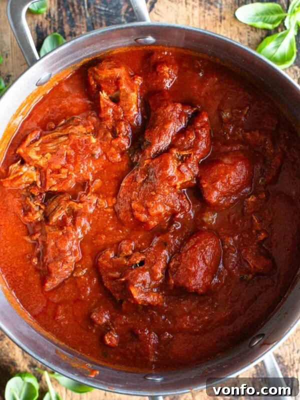 Slow-Braised Eggplant and Sausage Ragu 8 An overhead shot of Sugo Napoletano (Neapolitan ragu) in a large pot sitting on a wooden surface.