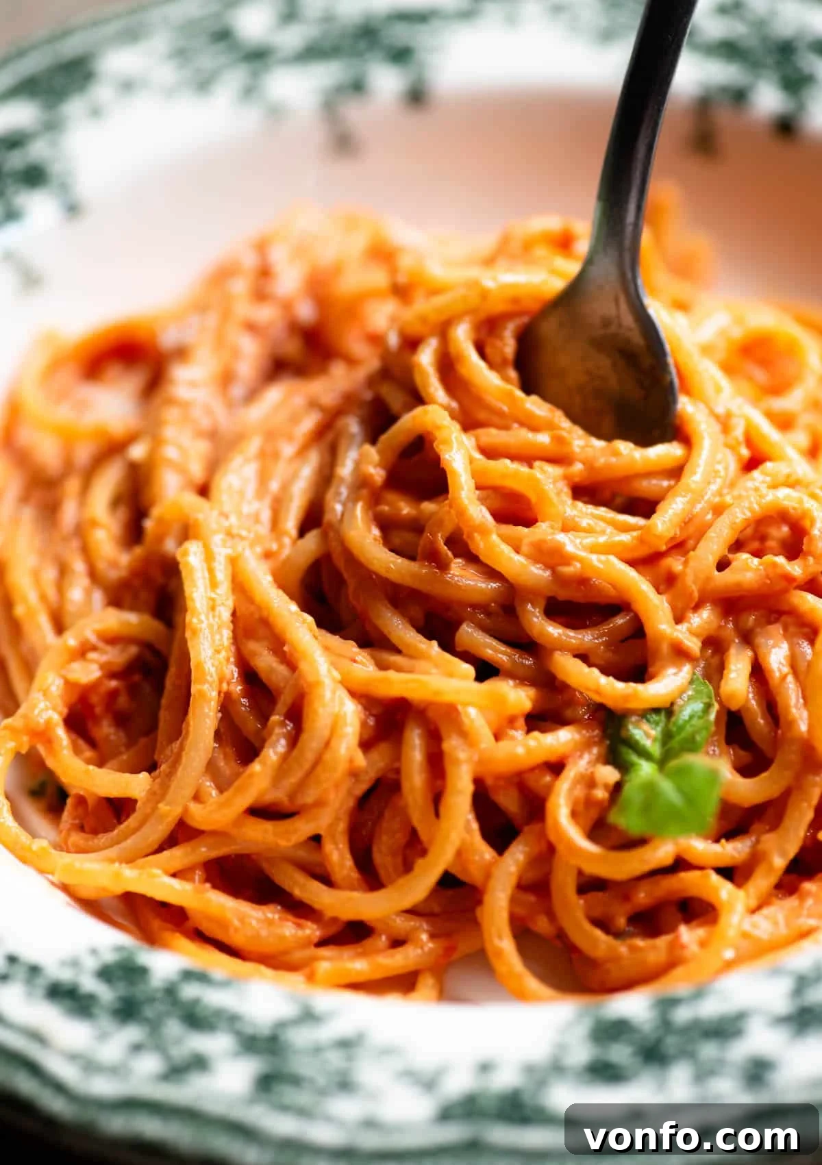 A close up of tomato and ricotta spaghetti in a bowl and twisted round a fork.