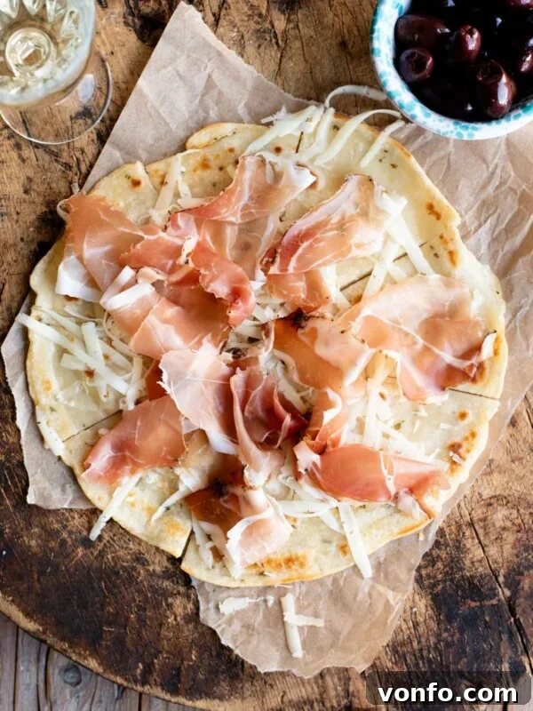 Danubio Salato: Neapolitan Savory Stuffed Brioche Buns 7 An overhead shot of Brustengo, an Italian flatbread topped with cured meat and cheese on a wooden board.